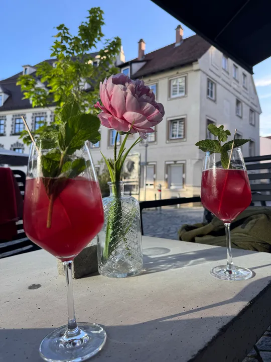 Zwei rote Getränke, rosa Blume, Außenszene.