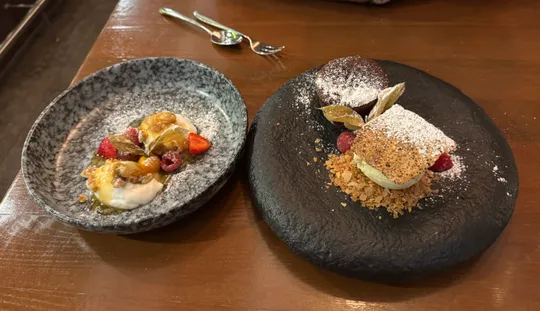 Zwei künstlerische Dessertteller auf Holztisch.