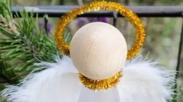 Christmas angel ornament with gold halo outdoors.