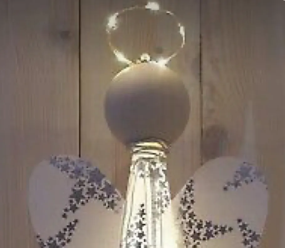 Angel ornament with lights on wooden background.