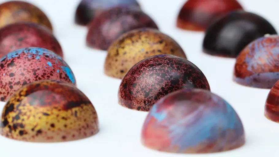 Colorful chocolate domes arranged on white surface.