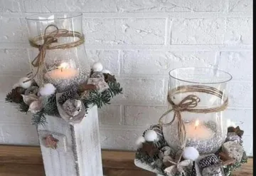 Candles in glass holders, decorated with greenery.