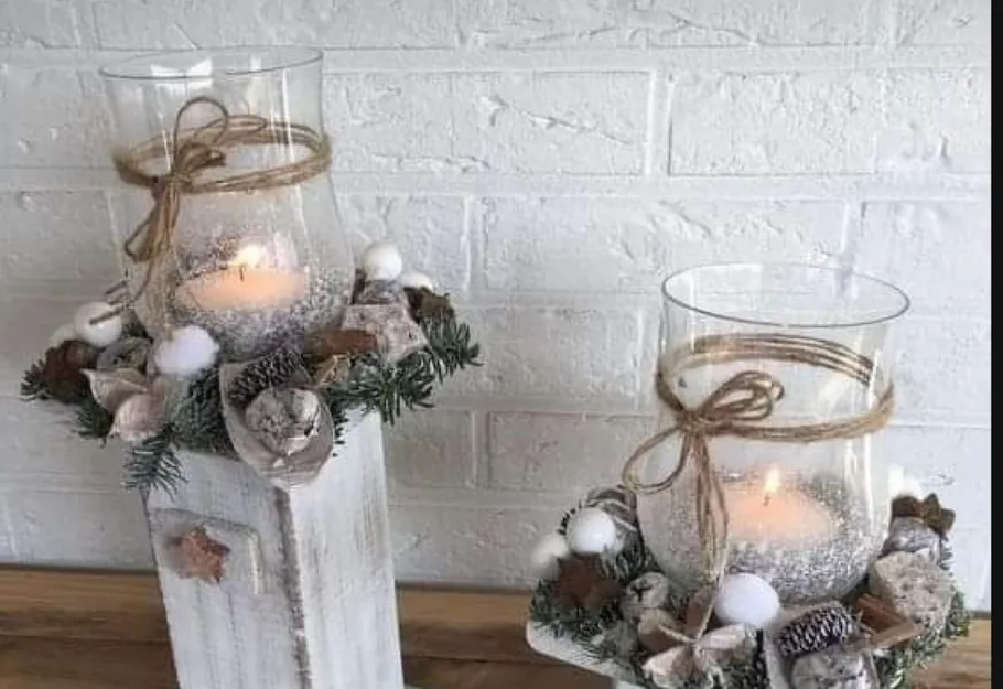 Candles in glass holders, decorated with greenery.