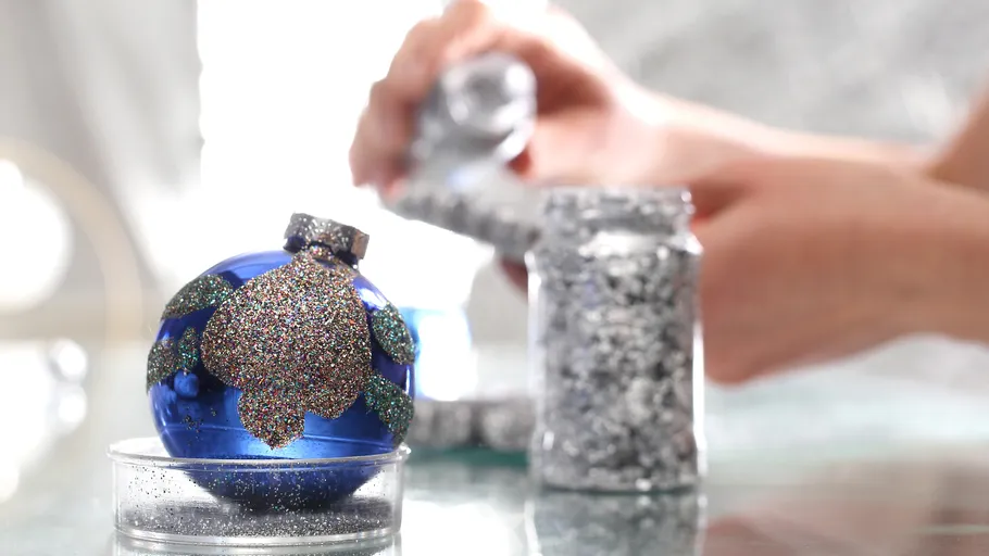 Blue ornament being decorated with glitter.