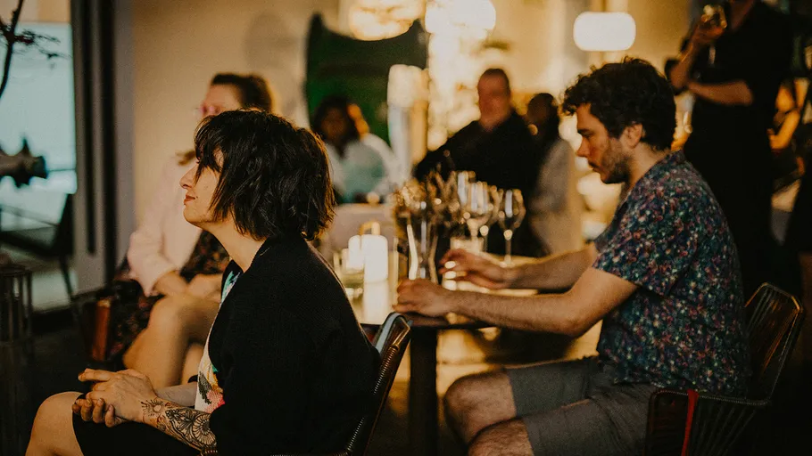 People sitting and listening in a dimly lit room.