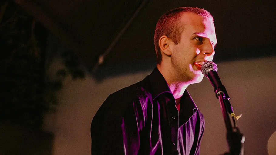 Person singing into microphone on stage.