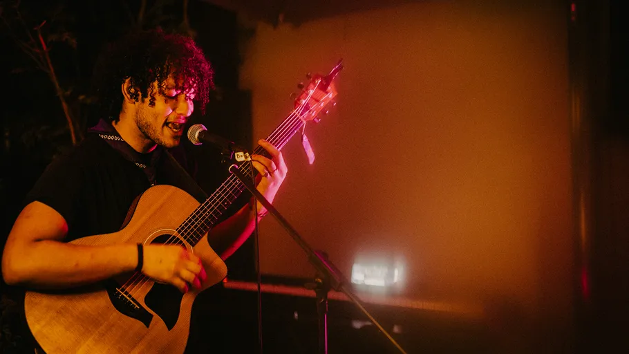 Musiker spielt Gitarre und singt auf Bühne.