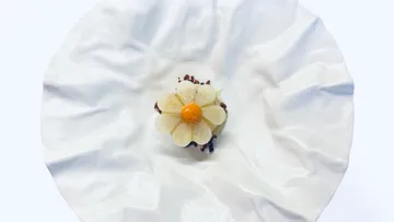 Flower-shaped dessert on a crumpled white plate.