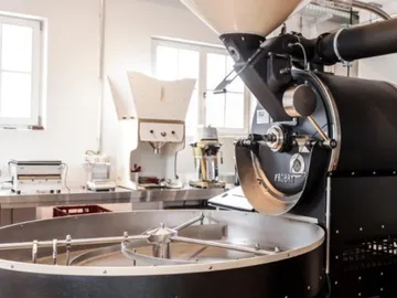 Kaffee-Röstmaschine dreht Bohnen in heller, moderner Umgebung.