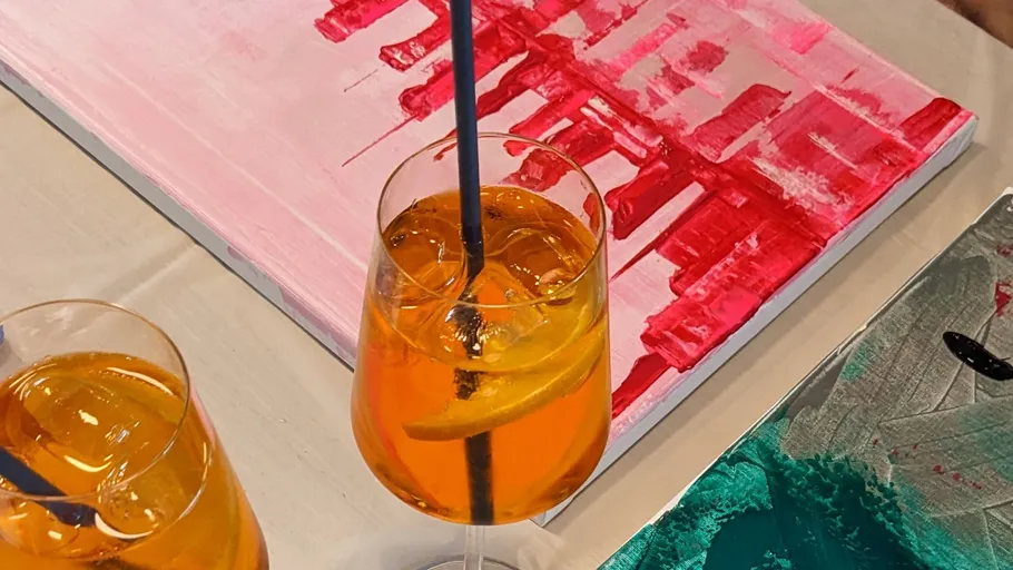 Zwei Orangendrinks neben abstrakten Gemälden.