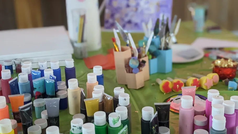 Bunte Farben und Pinsel auf grünem Tisch.