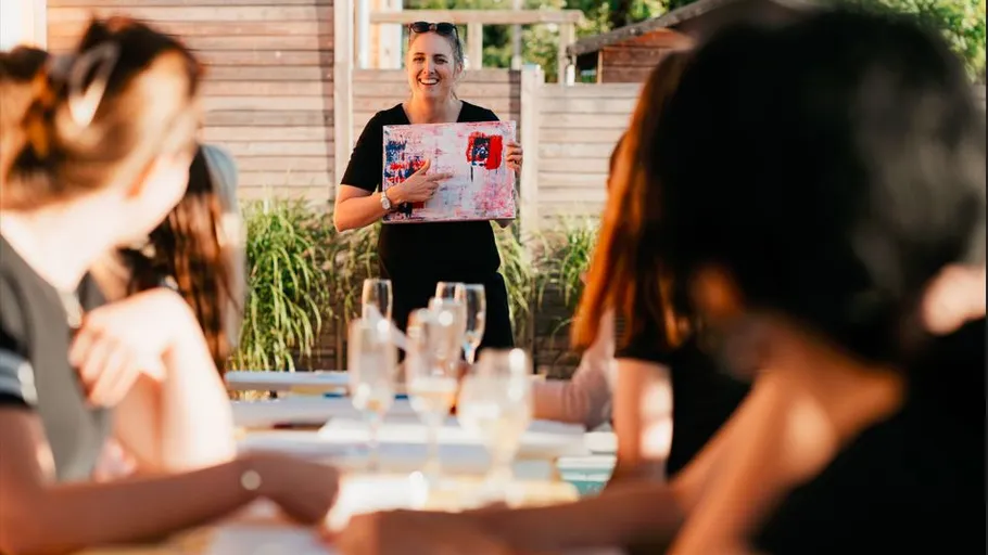 Woman showing artwork to seated group outdoors.