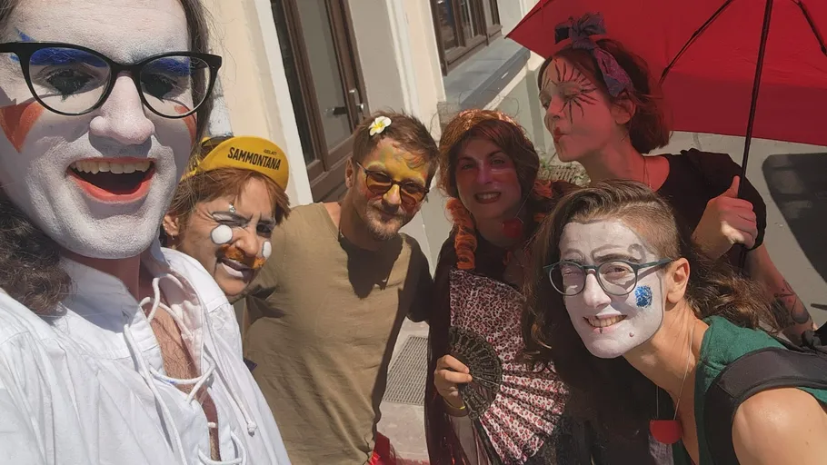 Gruppe mit Gesichtsbemalung vor Gebäude.