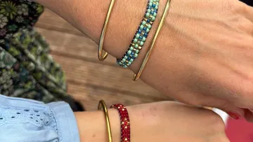 Arms wearing bracelets with wooden background.
