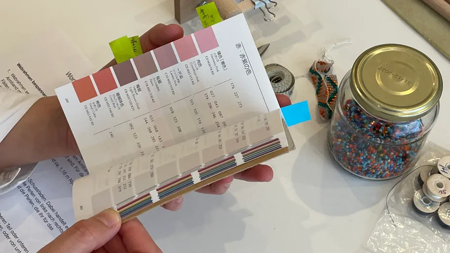 Hand hält Farbfächerbuch auf Tisch.