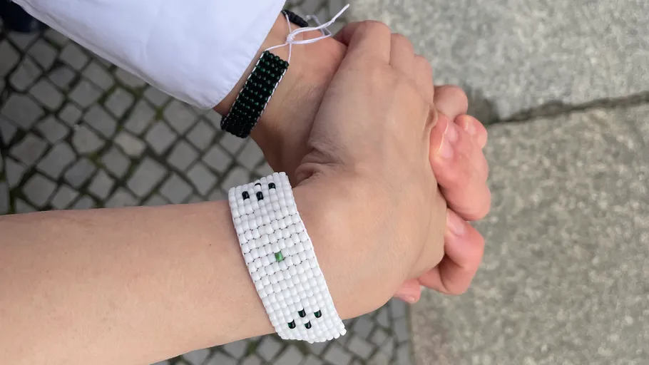 Two hands with bead bracelets holding each other.