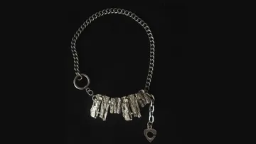 Silver necklace with textured metal pieces on black.