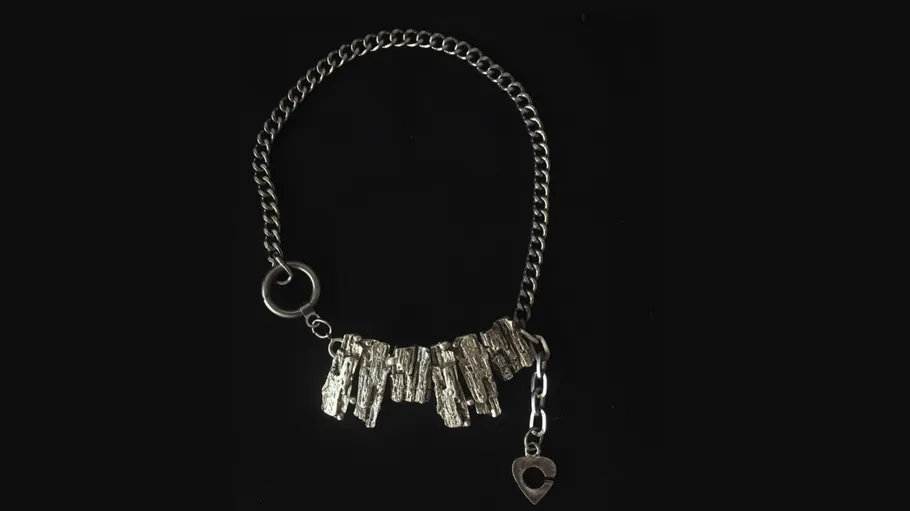 Silver necklace with textured metal pieces on black.