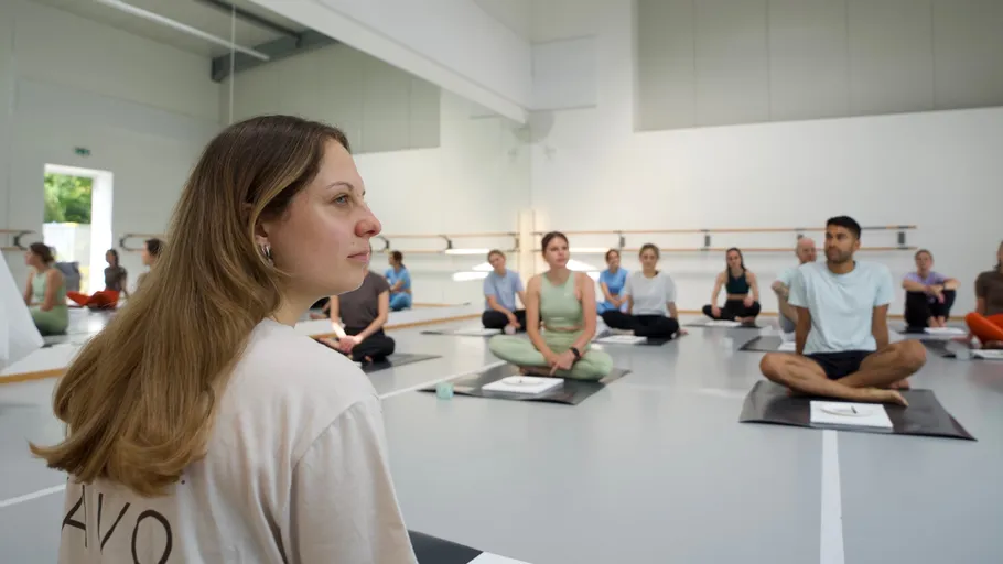 People sitting on yoga mats in a studio.