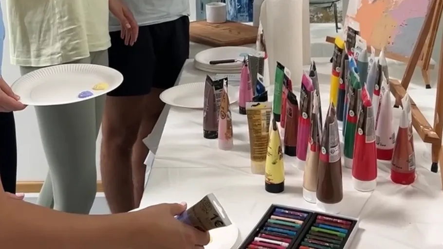 Personen wählen Farbtuben auf einem Tisch.
