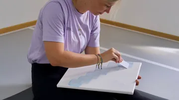 Frau klebt Formen auf Leinwand in Innenraum.