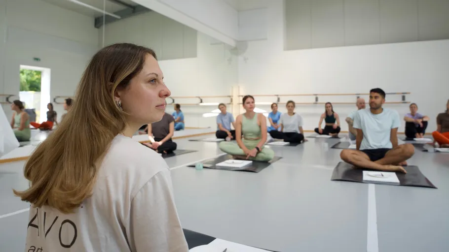 People sitting on yoga mats in a studio.