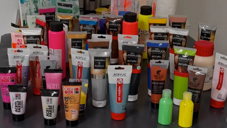 Assorted acrylic paint tubes on a table.