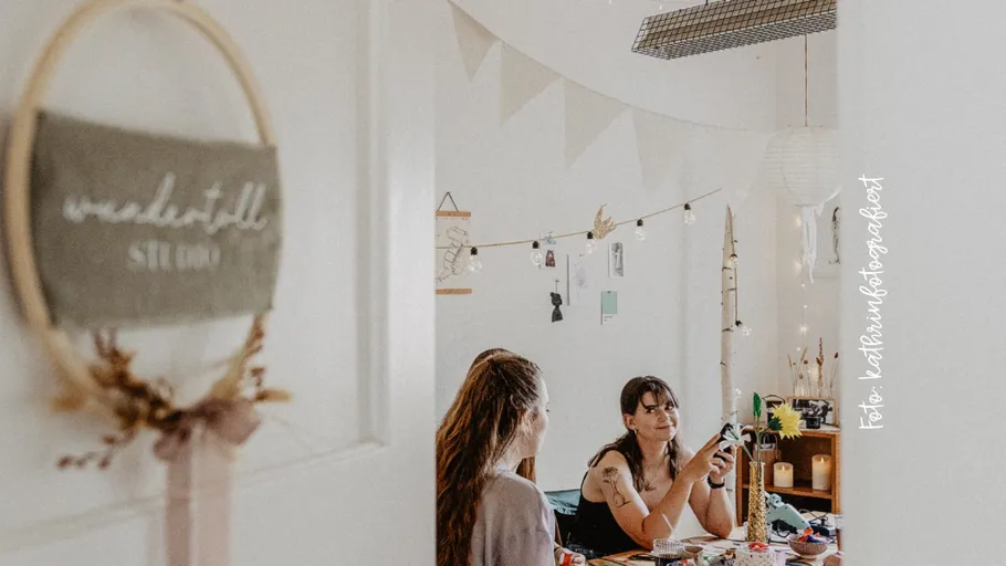 Two women crafting in a decorated room.
