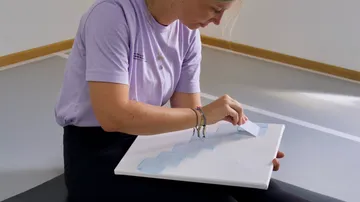 Person creating art on canvas indoors.