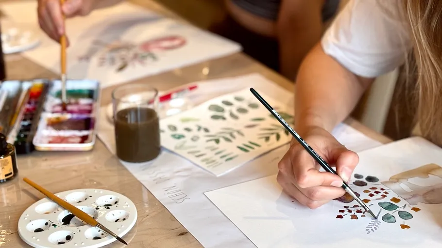 Person painting nature art at a table.