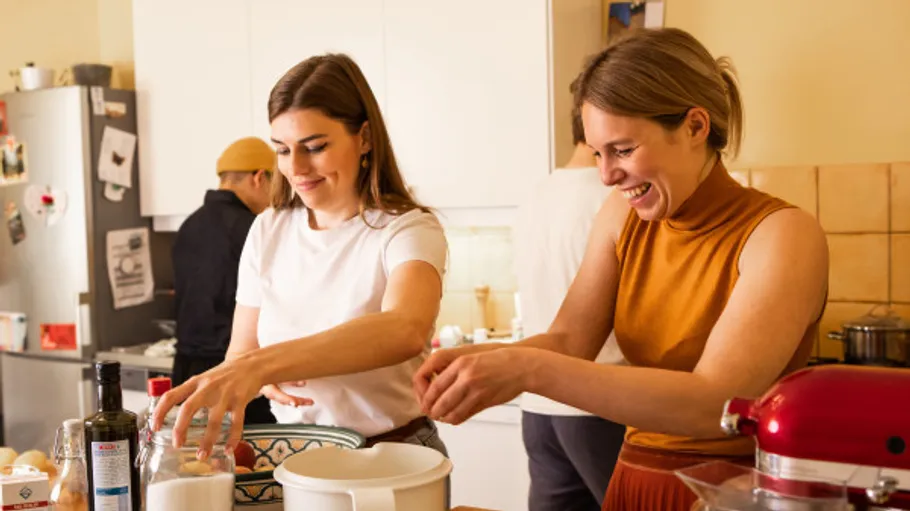 Two women cooking in a kitchen, smiling.