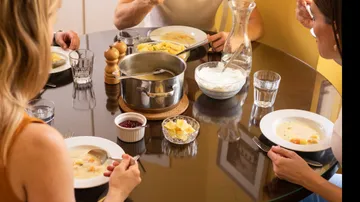 People eating soup at a dining table.