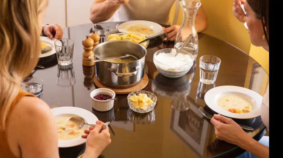 Menschen essen Suppe an einem Esstisch.