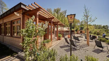 Holzgebäude mit Terrasse und Liegestühlen draußen.