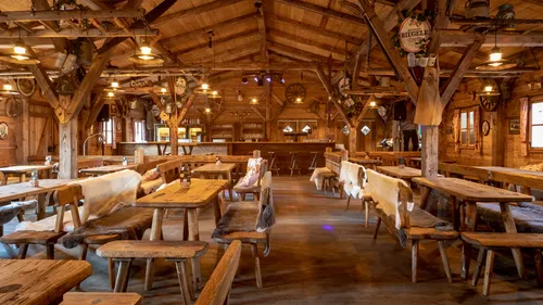 Rustic wooden tavern with tables and benches.