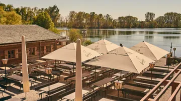 Outdoor beer garden with tables by a lake.