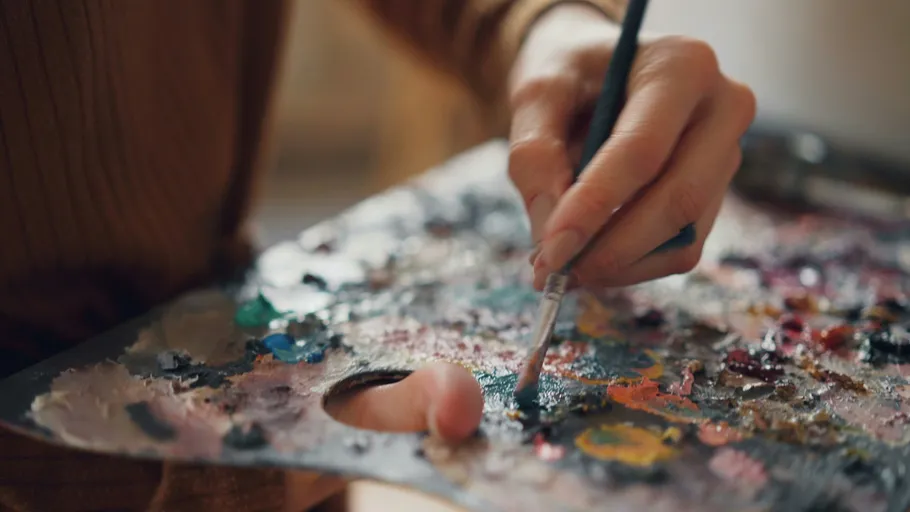 Hand malt mit Pinsel auf Palette.