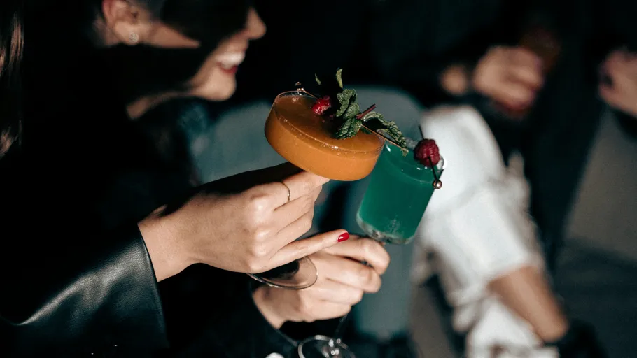 People holding colorful cocktails at a party.