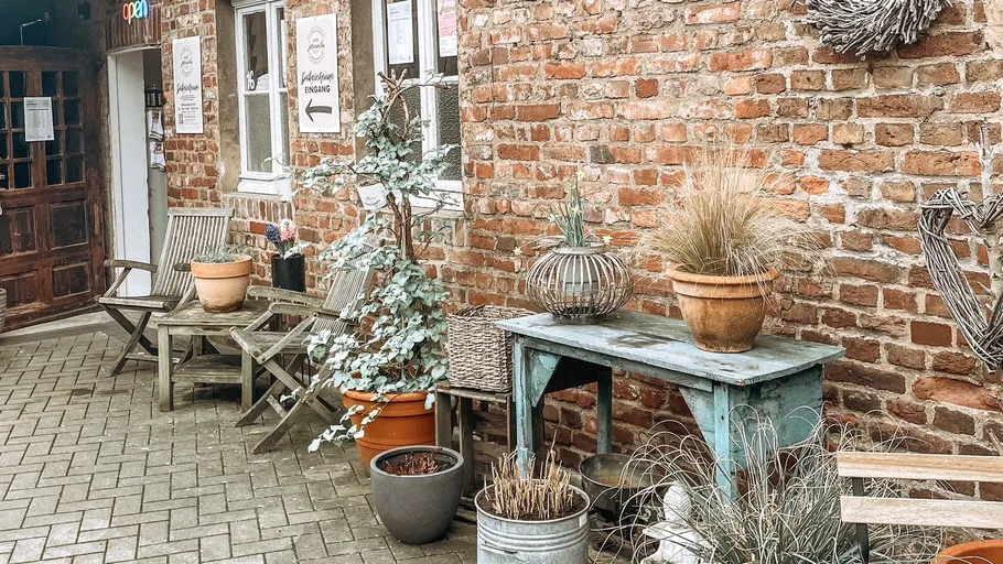 Rustikaler Patio mit Pflanzen und Holzmöbeln.