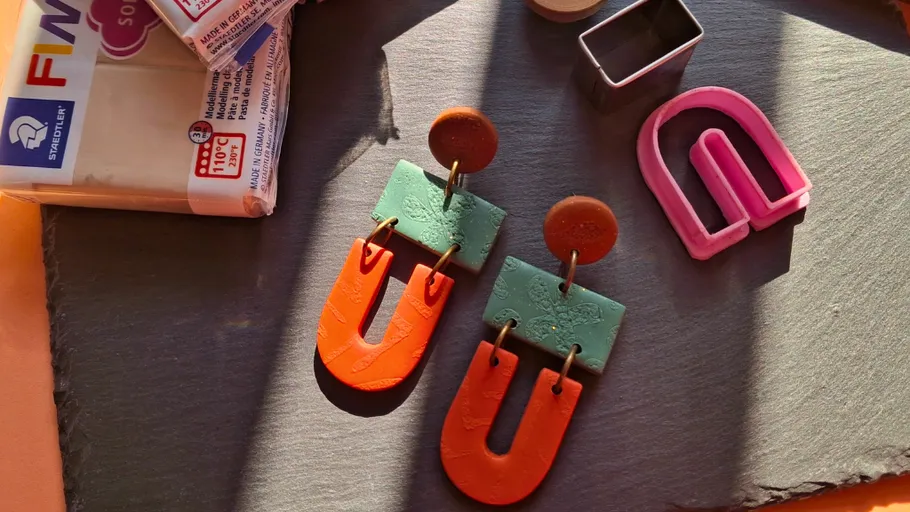 Colorful clay earrings beside clay and cutter.