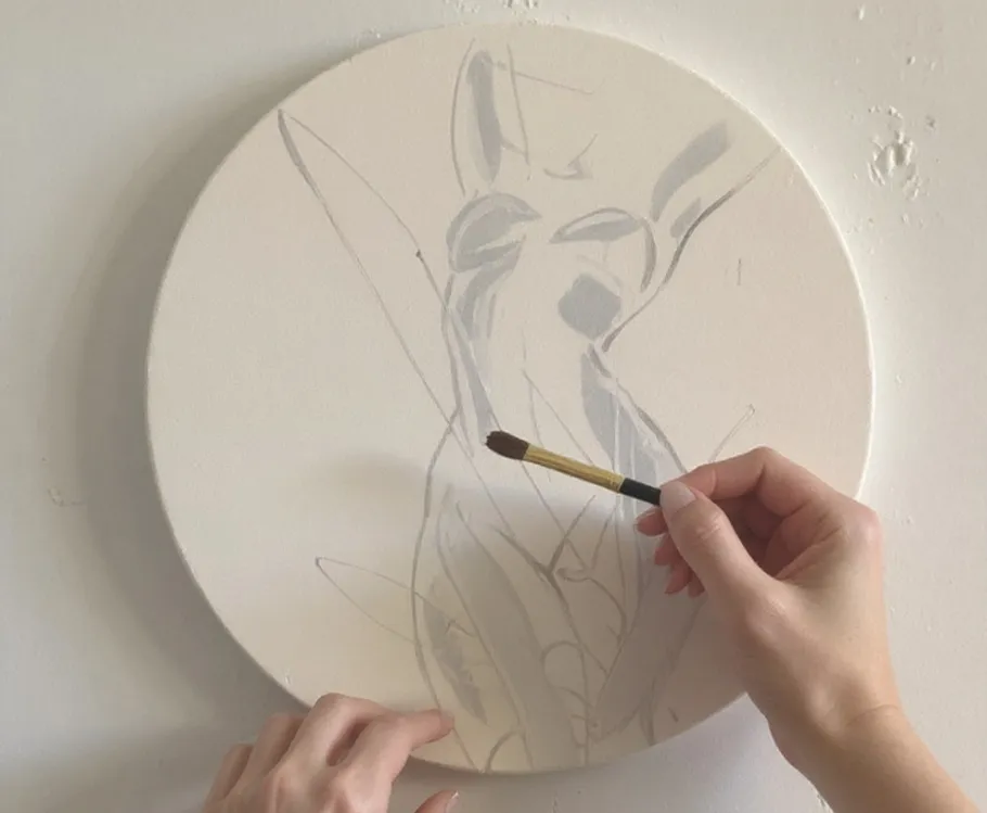 Hands painting abstract figure on round canvas.