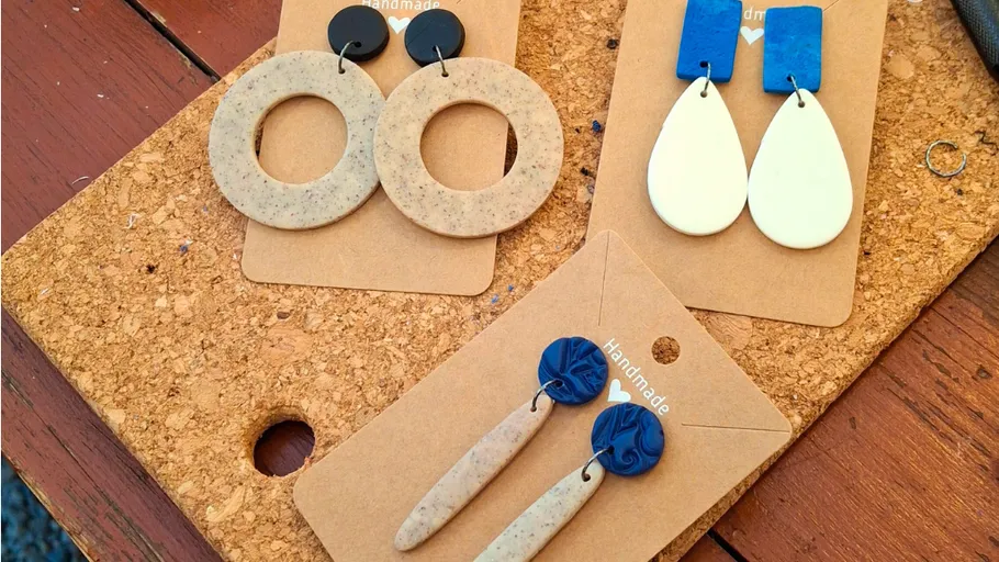Handmade earrings displayed on cork board.