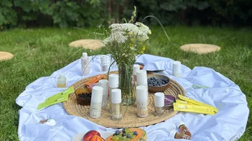 Picknickaufbau mit Kosmetik und Obst auf Gras.