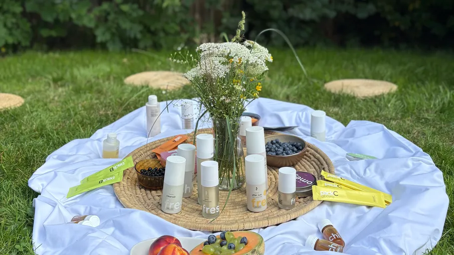 Picknickaufbau mit Kosmetik und Obst auf Gras.