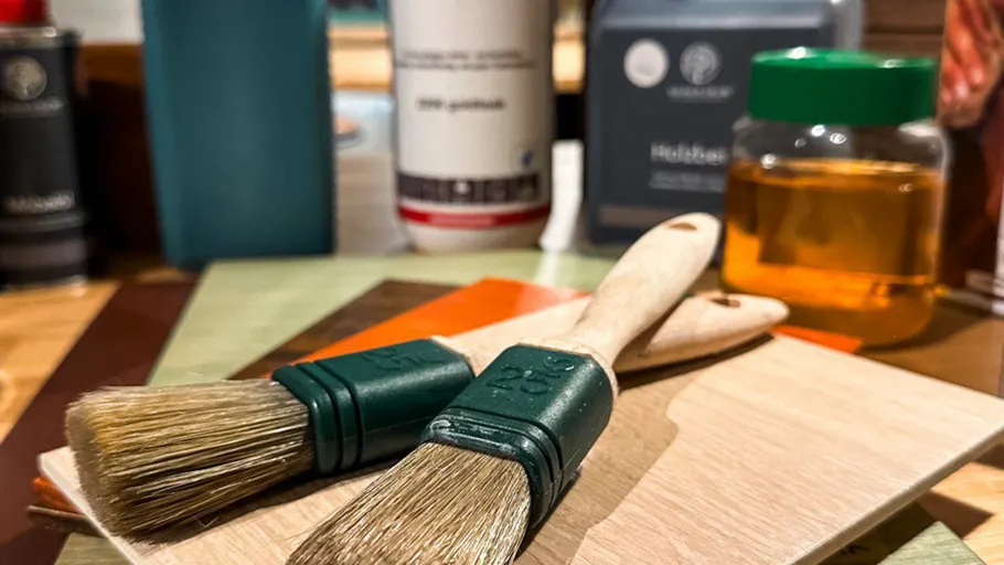 Paintbrushes on a wooden surface with paint cans.