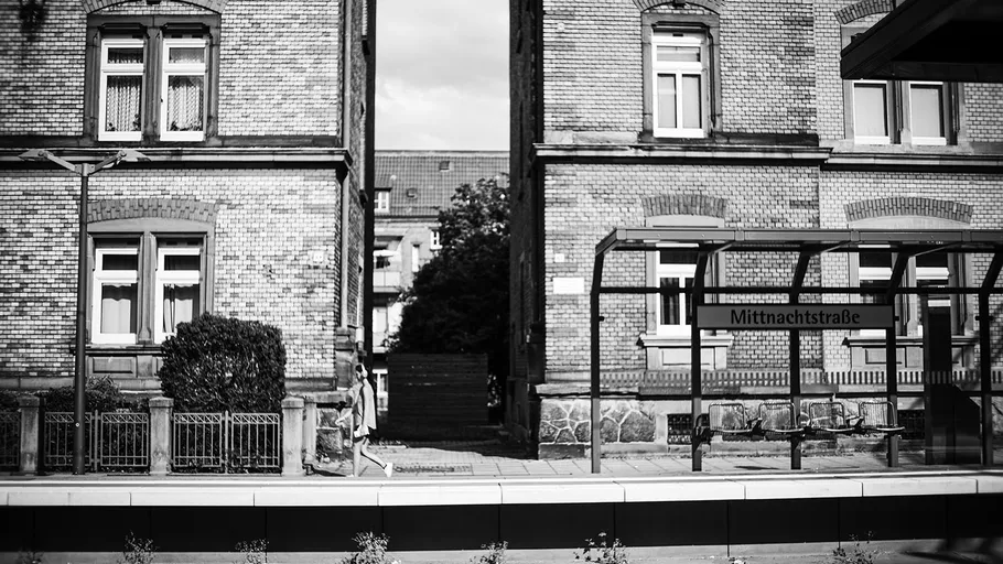 Bushaltestelle in der Nähe von Ziegelgebäuden mit Schild.
