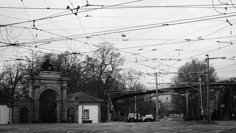 Empty street with overhead tram cables, archway entrance.