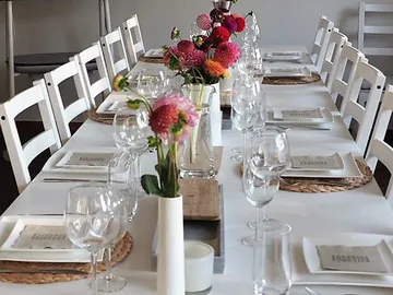 Ein gedeckter Tisch mit Gläsern und Blumen in Vasen.