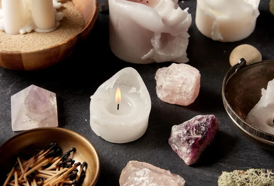 Candles and crystals on a dark surface.