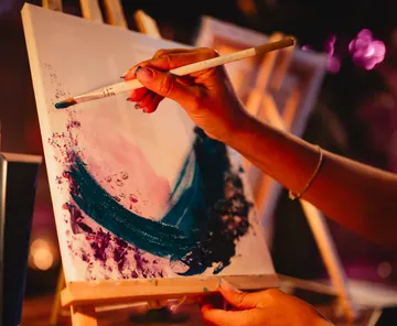 Person painting abstract art on canvas.